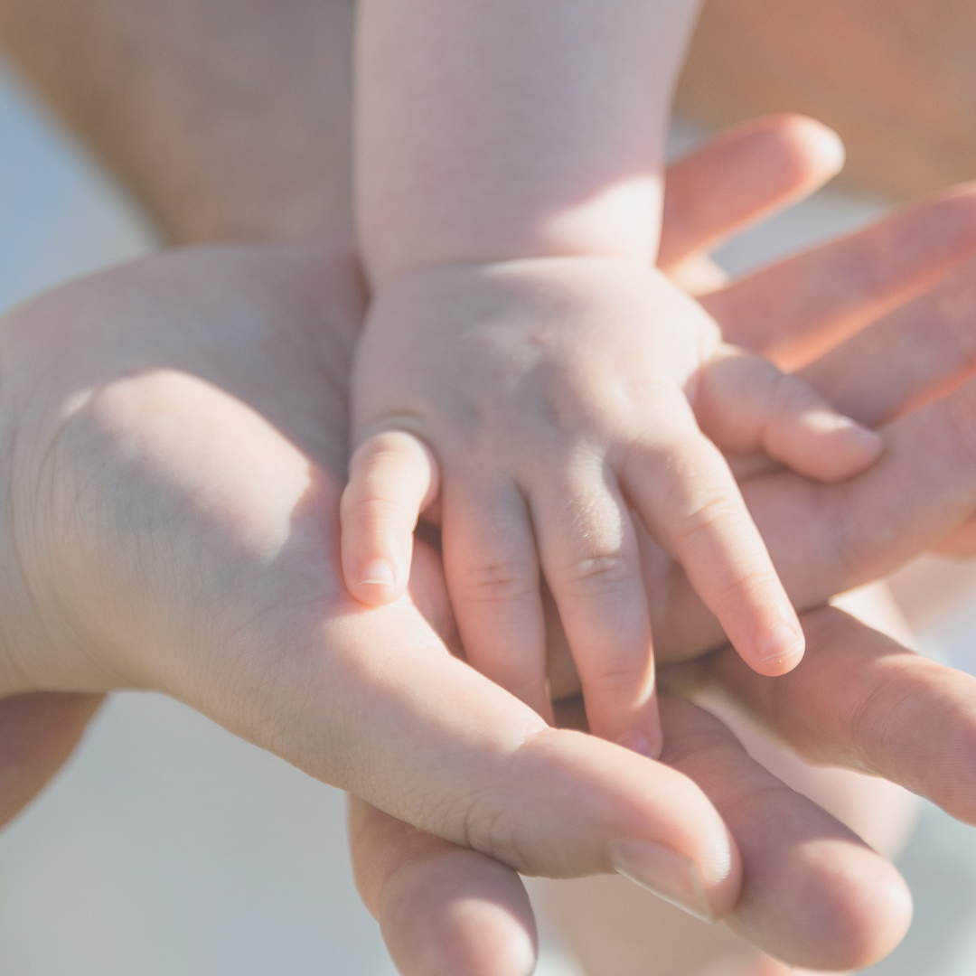 mano de bebé sobre manos de adultos