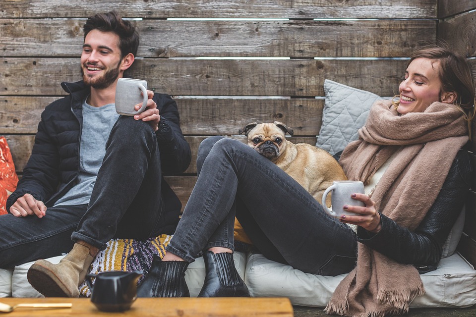 parejas dos jóvenes con un perro riendo mientras toman café